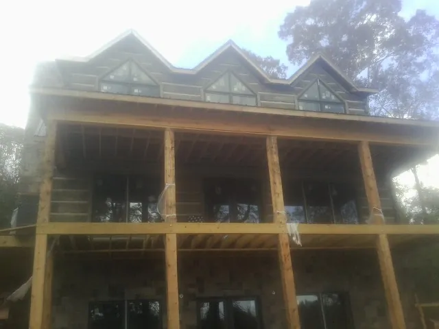 Dormers and porch framing on a large log home under construction — Roof Coating work by our crew in Alton