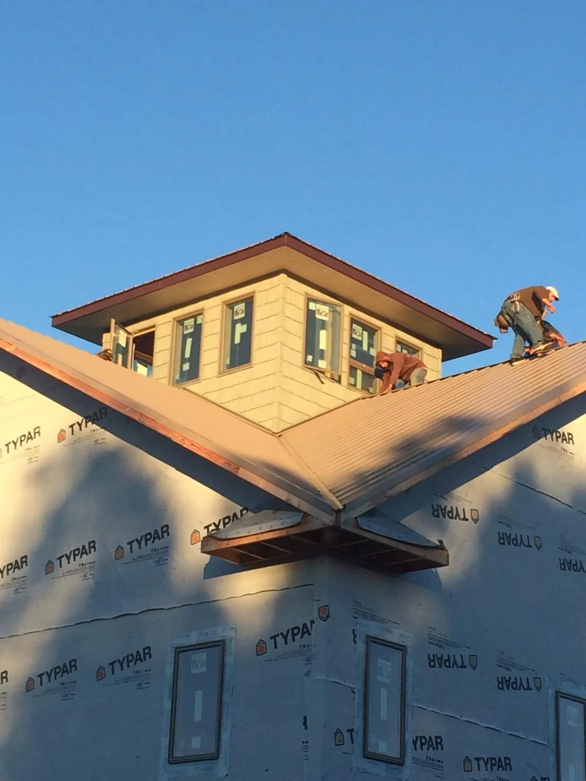 Roofers working around a rooftop cupola on a new metal roof at sunset — Roof Waterproofing in Alton by Roofing Brothers